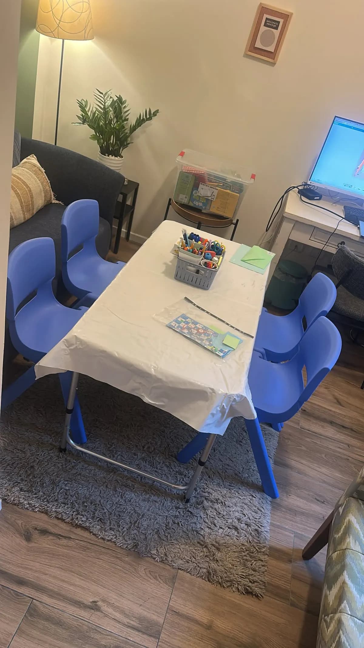 חדר הקבוצה: שולחן לבן, כיסאות כחולים לילדים וקלמר משותף